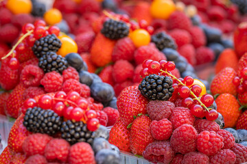 Berries background (raspberry, blueberry, strawberry, red currant, blackberry, golden berry). Baskets with fresh juicy berries on street market. 