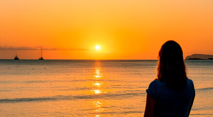 Fototapeta premium a woman watching a sunset on a torpical beach generated with artificial intelligence