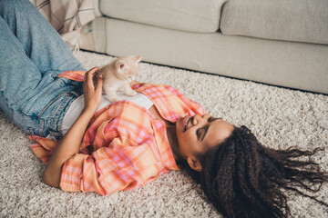 Photo of shiny cute girl dressed orange shirt smiling enjoying her little friend lying foor indoors house apartment room