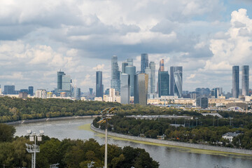 Obraz premium A breathtaking view of the modern Moscow City skyline framed by lush parkland and the winding river, creating a peaceful urban escape