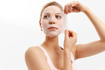 Cute smiling woman uses a tissue mask and enjoys soft and moisturized skin