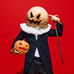 Portrait of creepy character in Victorian style clothes, in carved masks, with cane, posing with...