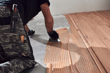 Professional handyman installing laminate flooring in a new apartment.
