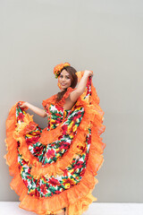 Woman in traditional Latin American dance dress posing with orange floral outfit