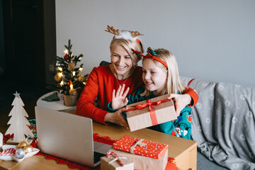 Mother and daughter celebrating Christmas virtually with loved ones. Virtual celebrations, online connections, holiday video calls, digital Christmas traditions, staying connected.