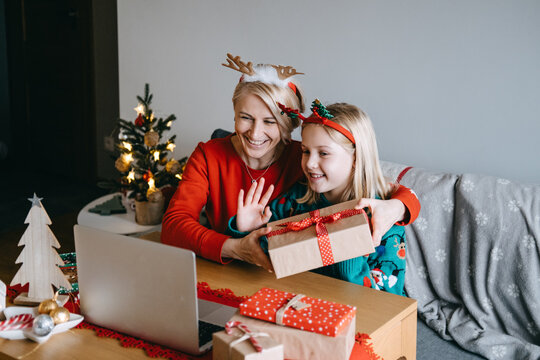 Mother and daughter celebrating Christmas virtually with loved ones. Virtual celebrations, online connections, holiday video calls, digital Christmas traditions, staying connected.