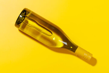 A white wine bottle placed flat on a yellow background