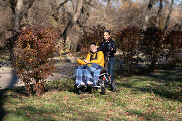 Siblings enjoying outdoor time in park, child in wheelchair, sibling support, family bond, disability inclusion, special needs care.