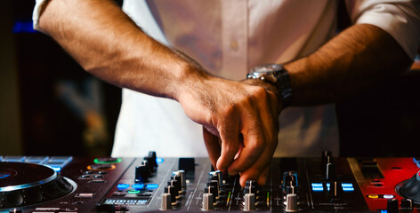 Close up DJ plays live set and mixing music on turntable console in the night club. Disc Jokey...