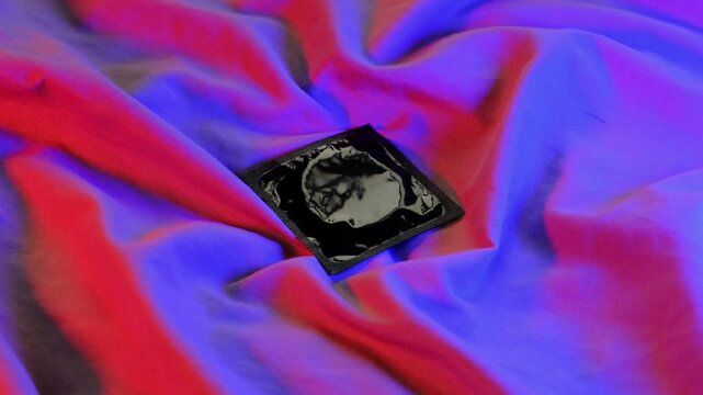 Contraception. Condom on bed. Safe sex. Intimate colorful atmosphere.