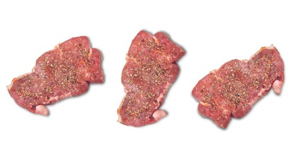 Top view of three raw, seasoned beef steaks, coated with a mix of fresh herbs and aromatic spices, isolated on white background.