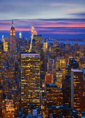 Detailed image of a city skyline at dusk with lights on.

