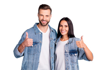 Portrait of charming spouses showing thumb up wearing denim jeans isolated over blue background