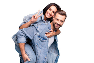 Portrait of cute man carrying his sweetheart making v-signs wearing denim jeans jacket isolated...