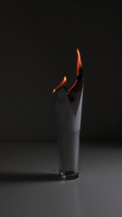 glass with burning paper in it on dark background.  dark mood photo. energy and passion. fast...