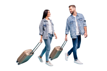 Full size profile side photo of two sweethearts carrying baggage seeing off wearing denim jeans jackets isolated over blue background