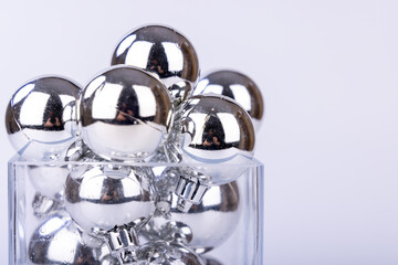 Decorative glass vase containing silver holiday balls in varying sizes, used as festive Christmas ornaments