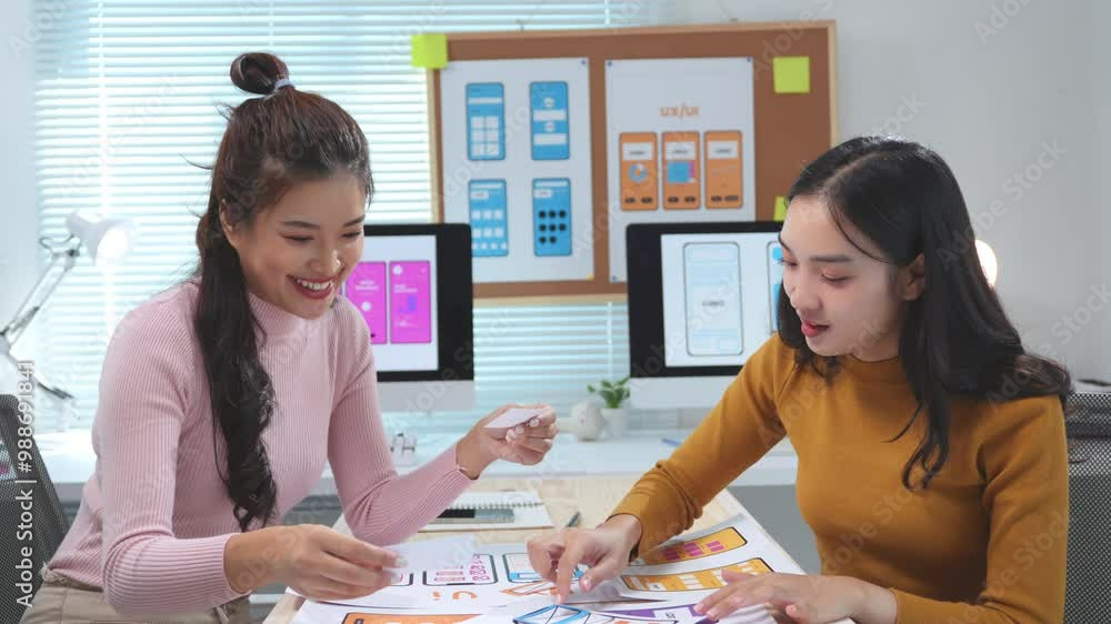 Aufkleber two asian women are working on a mobile application prototype in their office. they are discussing f