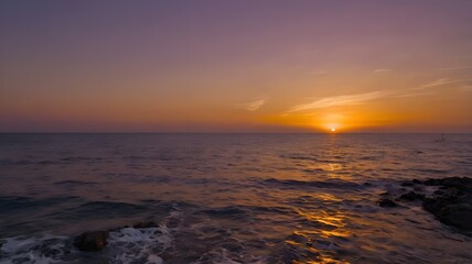 Fototapeta premium Sunset over the sea, highlighting a vibrant orange, red, and purple evening sky, with ocean water gently rippling, offering a beautiful wallpaper background