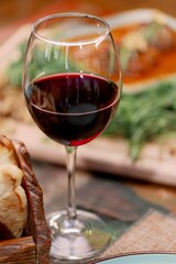 Close-up of red wine with food in the background.