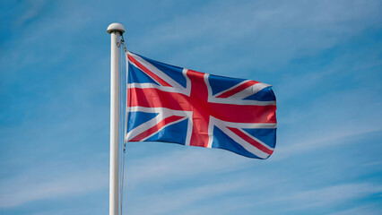 Union Jack Flag Waving Majestically Against a Clear Blue Sky on a Flagpole