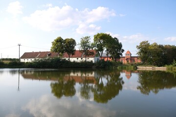 Rural scenery with reflection of buildings in pond. Wysoka village in Warmia, Poland