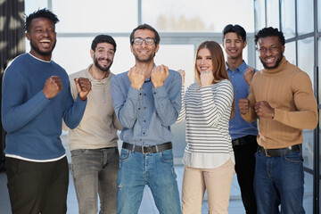 Fototapeta premium Group of happy managers rejoice at a successful deal by clenching their hands into fists and raising them up