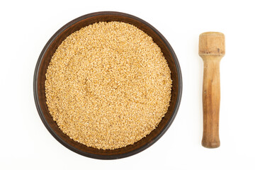 Flax seeds in a plate and a wooden masher on a white table