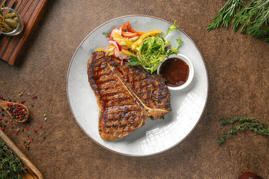Portion of grilled beef t bone steak with salad