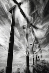 Windmills spin in wind at wind farm, creating dynamic and powerful scene. dramatic black and white filter enhances movement and energy of turbines