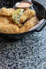 golden deep-fried battered chicken nuggets.succulent chicken chunks ensconced in a delectable batter, crisped up with Panko, and draped in sauce closeup on the plate on the table.