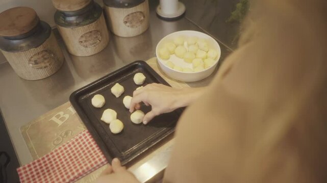 Person preparing traditional chipa bread on a baking tray in a home kitchen, capturing the warmth and authenticity of homemade baking