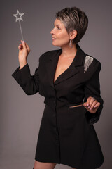 A businesswoman poses in a photo studio in a silver jumpsuit and a black stiletto dress.