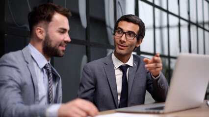 Young designer giving some new ideas about project to his partners in conference room