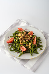 Vibrant green bean salad with fresh tomatoes and crunchy nuts on an elegant plate, perfect for a healthy lunch or dinner