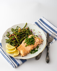 Deliciously plated salmon with green beans, pine nuts, and lemon slices on a floral-patterned dish...