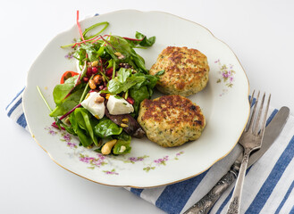 Delicious herb-infused fish cakes served with a vibrant garden salad on an elegant vintage plate