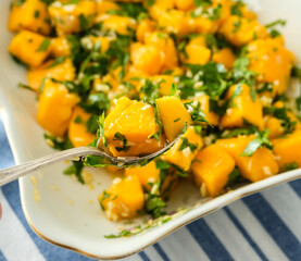 Fresh mango salad with chopped herbs and a hint of lime enjoyed in a sunny kitchen setting during a summer gathering