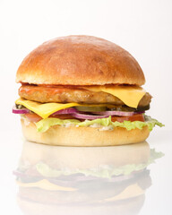 Delicious freshly made cheeseburger with layers of colorful toppings on a clean white surface