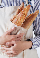 Freshly baked baguettes embraced by a joyful baker in a light-filled kitchen, celebrating the art of bread-making