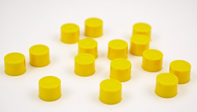 A bunch of yellow plastic knobs on a white surface.