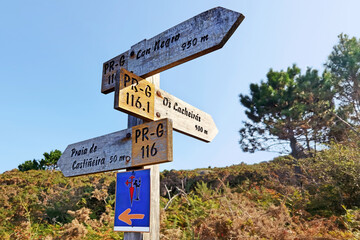 wooden signal with yellow arrow on Camino do Salnes de Santiago in O Grove village for pilgrimage to Compostela, Spain