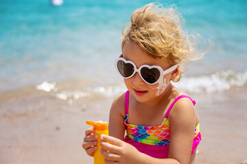 Child applying sunscreen to face. Selective focus.