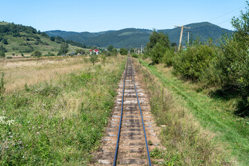 Narrow gauge railway in a mountain village. Rails and sleepers. Railway track. Nature in summer....