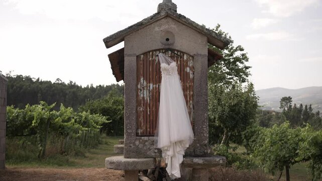 wedding dress hangs from a traditional stone espigueiro, with lush vineyards in the backdrop