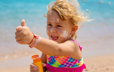 Child applying sunscreen to face. Selective focus.