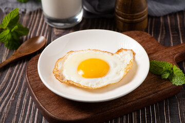 fried egg in a white plate on table.