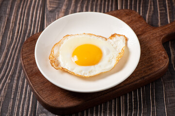fried egg in a white plate on table.