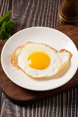 fried egg in a white plate on table.