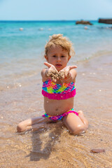 Child playing with sand on the beach at sea. Selective focus.
